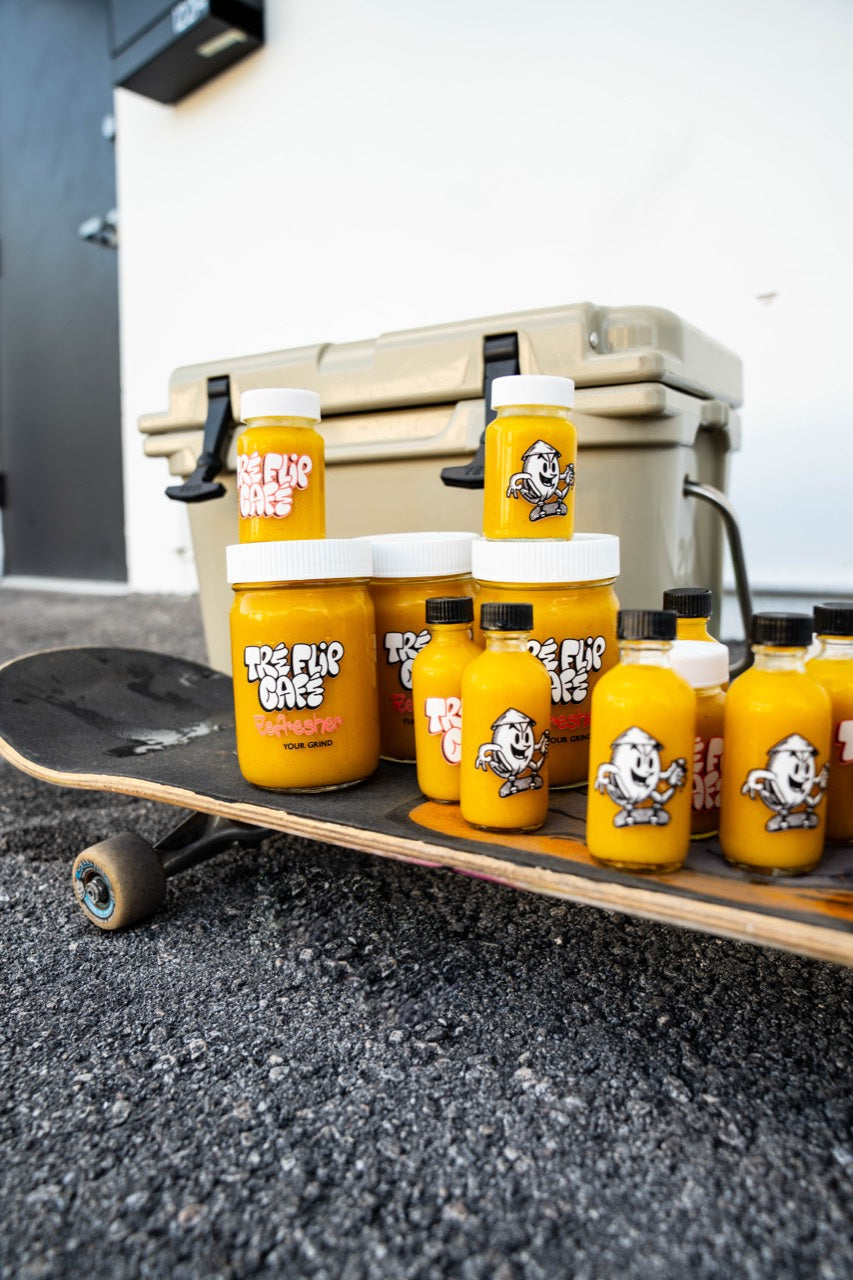 Tre Flip Cafe Classic Ginger OG shots and 12 oz jars displayed on a skateboard