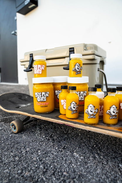 Tre Flip Cafe Classic Ginger OG shots and 12 oz jars displayed on a skateboard.