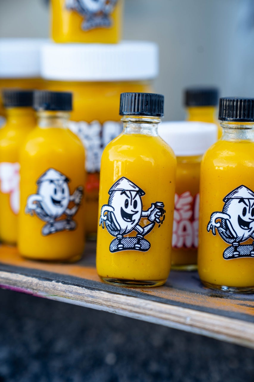 Close-up of golden Tre Flip Cafe Classic Ginger OG 2 oz shot bottles on a skateboard